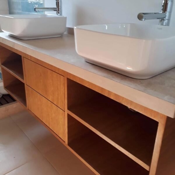Vanitory de tono madera con cajones centrales, estantes laterales y doble bacha de apoyo