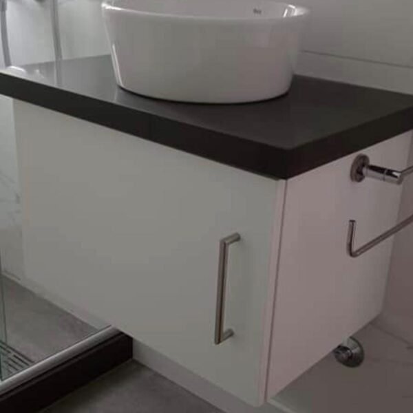 Vanitory flotante blanco con mesada negra, cajones y puertas con tiradores metálicos